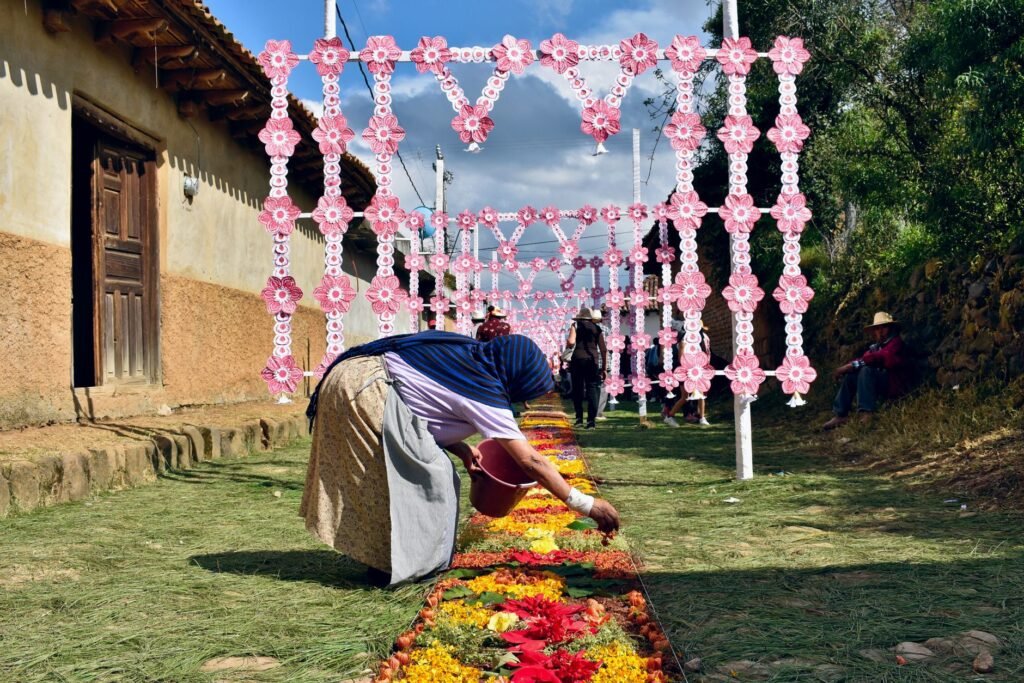 Persona elaborando una alfombra decorativa en el suelo de una calle durante una festividad