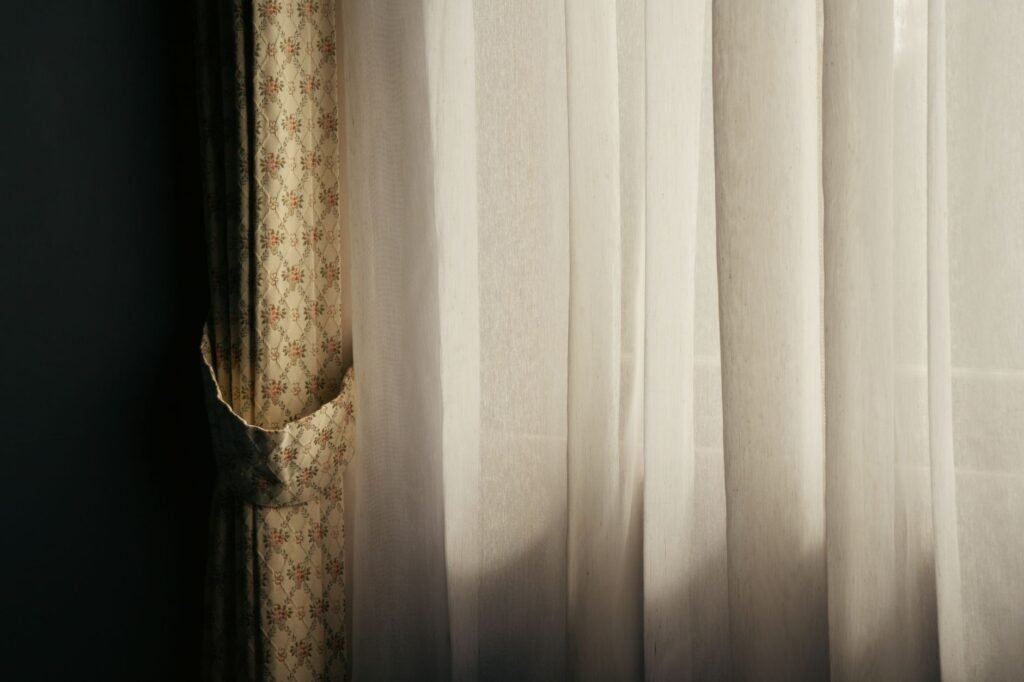 Cortinas de tela claras junto a una ventana, listas para tenir