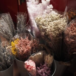 Ramos de flores secas teñidas en varios colores dentro de baldes