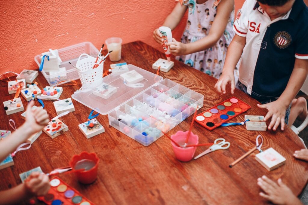 Niños pintando con colores alrededor de una mesa en el colegio