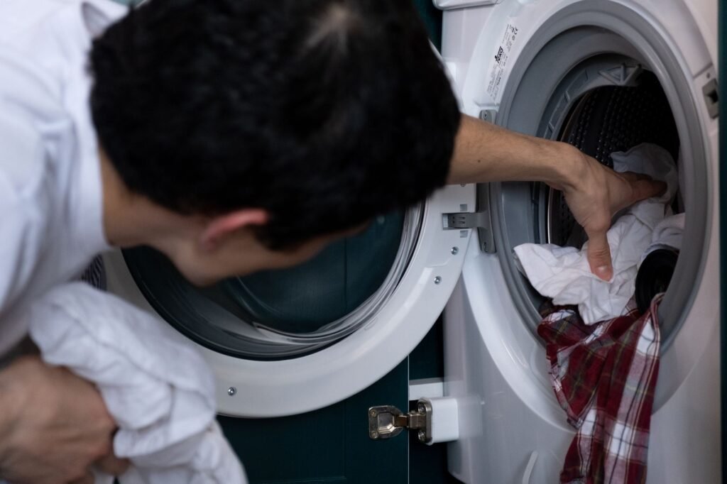 Persona metiendo ropa en una lavadora de carga frontal para teñir