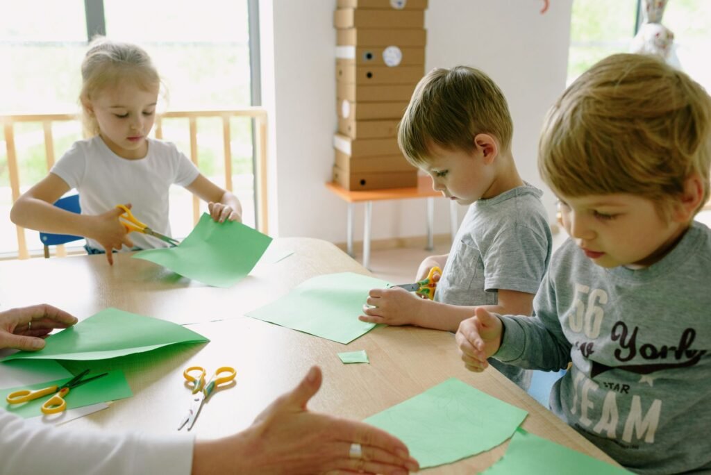 Grupo de niños haciendo manualidades con papel y tijeras en el aula